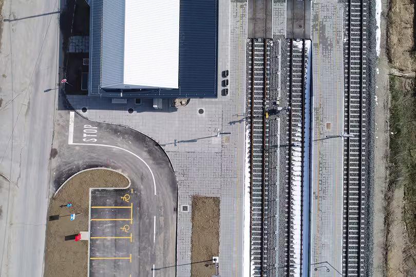 Snimak dronom iz ptičje perspektive koji prikazuje željezničku postaju, parking i pristupne ceste za potrebe praćenja gradilišta.